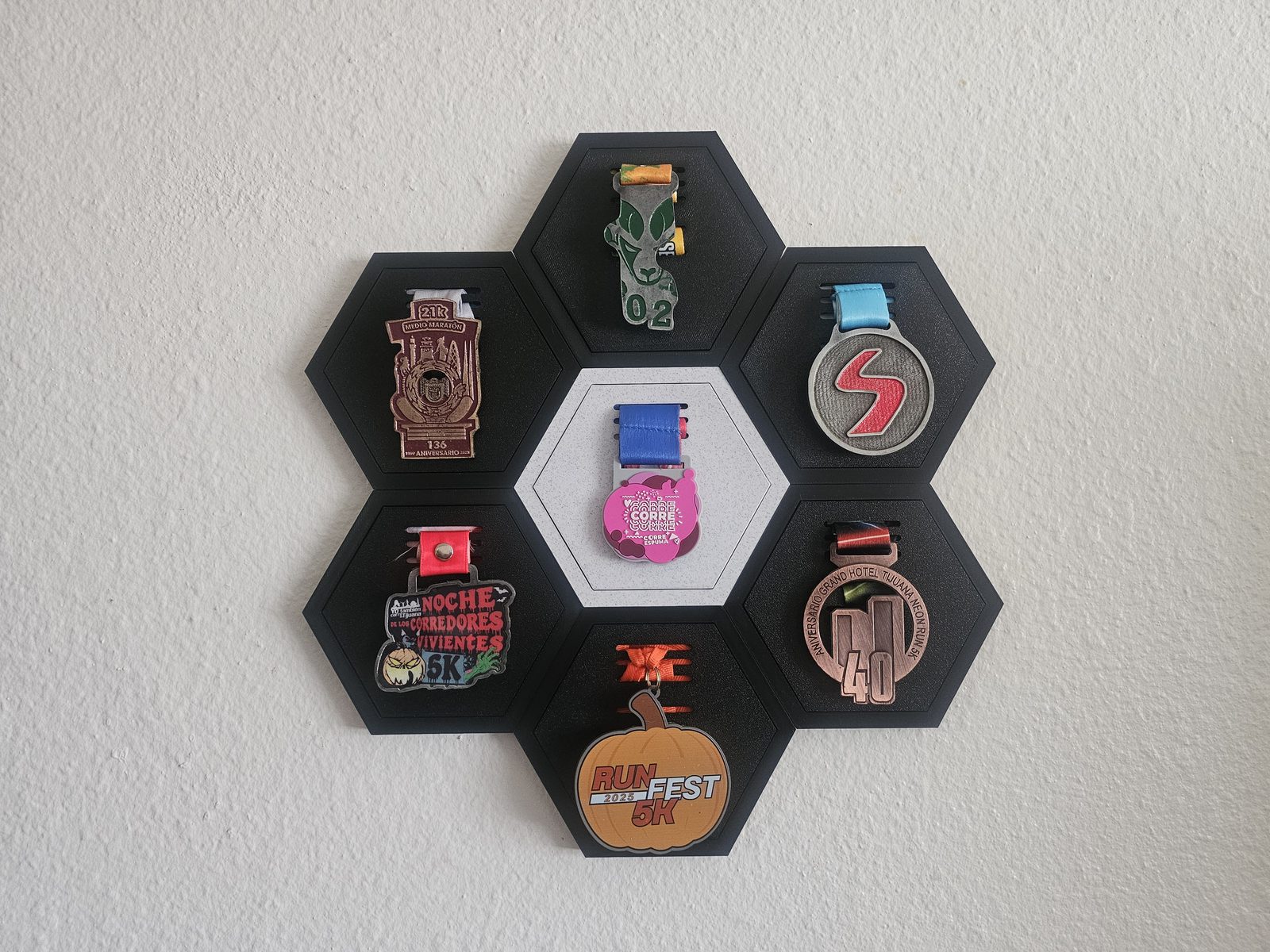 A 7-unit Hive Medal Co. honeycomb wall mounted with real race medals